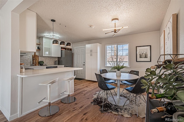 dining area with a notable chandelier, a textured ceiling, light hardwood / wood-style flooring, and sink