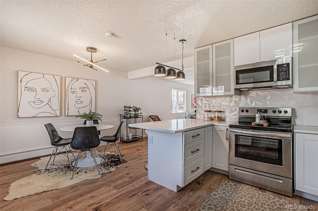 kitchen with stainless steel appliances, backsplash, white cabinetry, and wood-type flooring