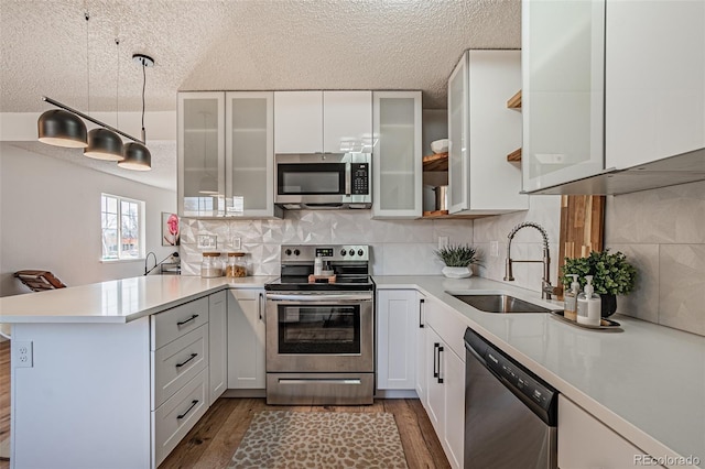 kitchen with stainless steel appliances, kitchen peninsula, tasteful backsplash, white cabinetry, and sink