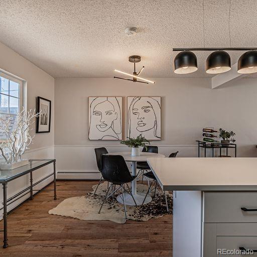 dining room featuring a chandelier, a textured ceiling, dark wood-type flooring, and a baseboard heating unit