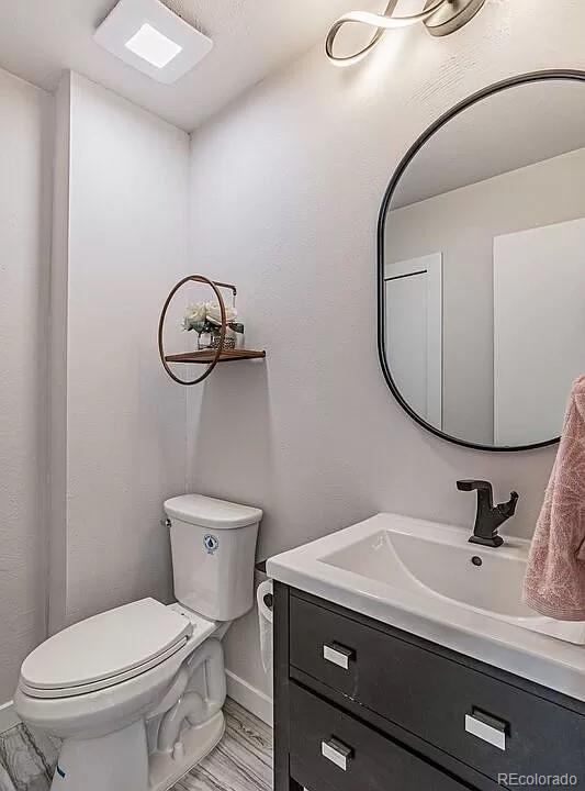 bathroom featuring toilet, hardwood / wood-style flooring, and vanity