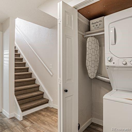 washroom featuring stacked washer / drying machine and hardwood / wood-style flooring