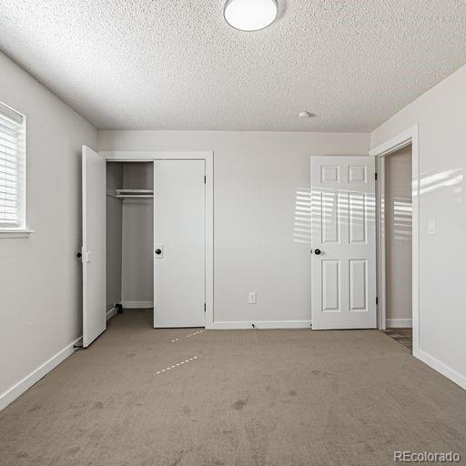 unfurnished bedroom with a closet, light carpet, and a textured ceiling