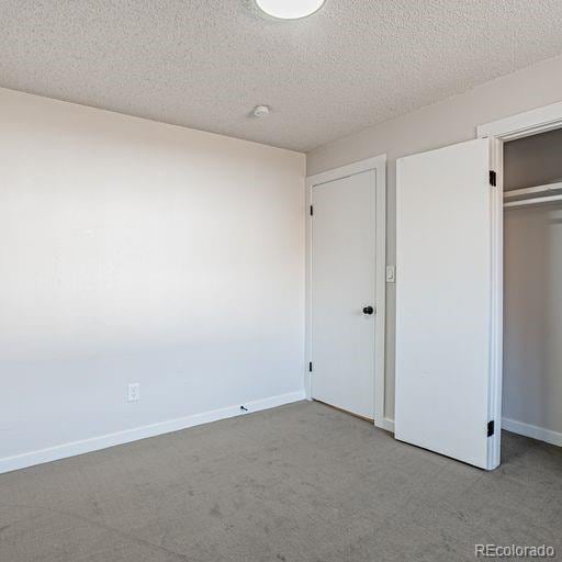 unfurnished bedroom featuring a closet, a textured ceiling, and light colored carpet