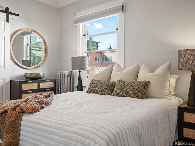 bedroom featuring a barn door and crown molding