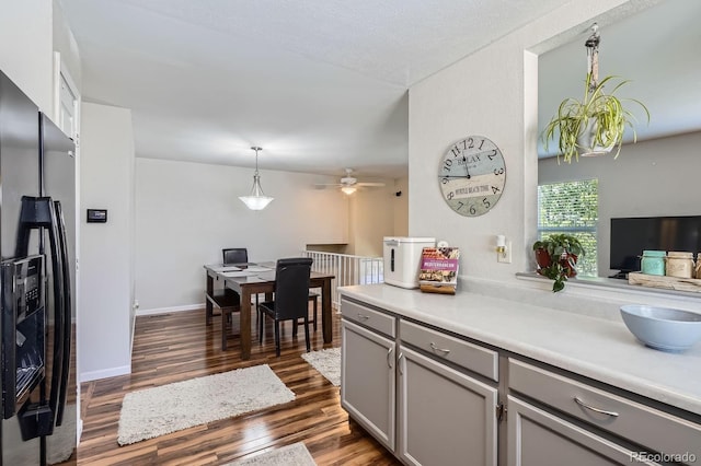 kitchen featuring fridge with ice dispenser, gray cabinets, dark wood finished floors, ceiling fan, and light countertops