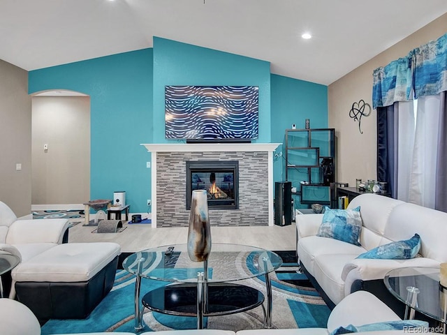 living room with a tiled fireplace, vaulted ceiling, and light hardwood / wood-style flooring