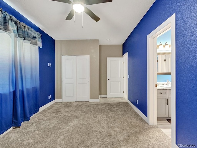 unfurnished bedroom featuring ceiling fan, light colored carpet, connected bathroom, and a closet