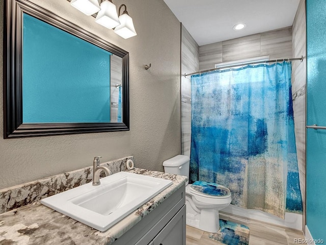 bathroom with walk in shower, vanity, and toilet