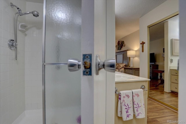 bathroom with a textured ceiling, vanity, walk in shower, and hardwood / wood-style floors