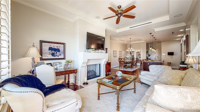 living area featuring a fireplace with raised hearth, crown molding, a tray ceiling, and wood finished floors