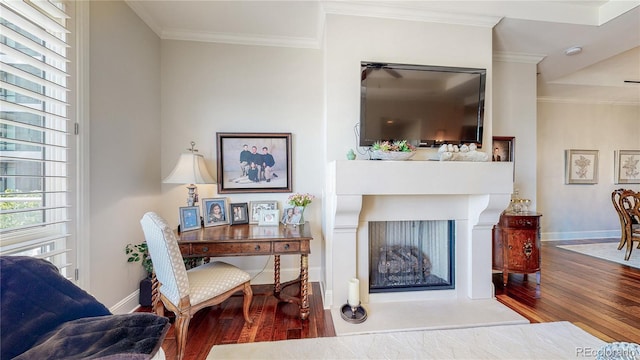 living area featuring a fireplace, crown molding, wood finished floors, and baseboards