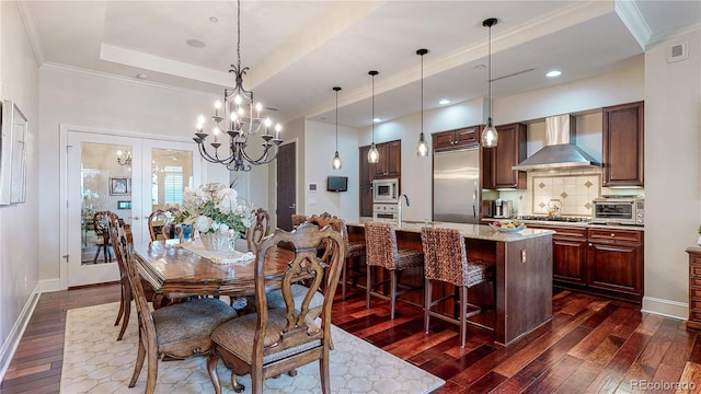 dining space with dark wood-type flooring, a notable chandelier, ornamental molding, a tray ceiling, and baseboards