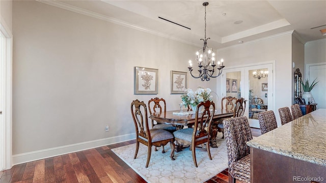 dining area featuring crown molding, baseboards, dark wood finished floors, a tray ceiling, and a notable chandelier