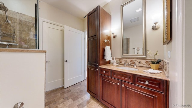 bathroom featuring vanity, visible vents, and tiled shower