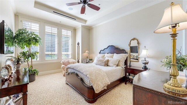 bedroom with baseboards, a tray ceiling, ceiling fan, light carpet, and crown molding