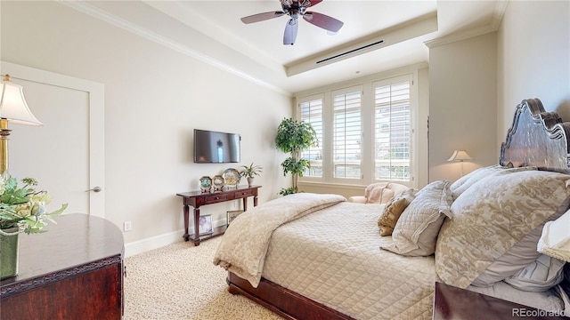 carpeted bedroom featuring a tray ceiling, baseboards, ornamental molding, and a ceiling fan