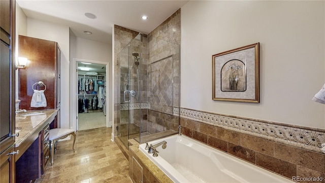 bathroom featuring vanity, a shower stall, a spacious closet, and a bath