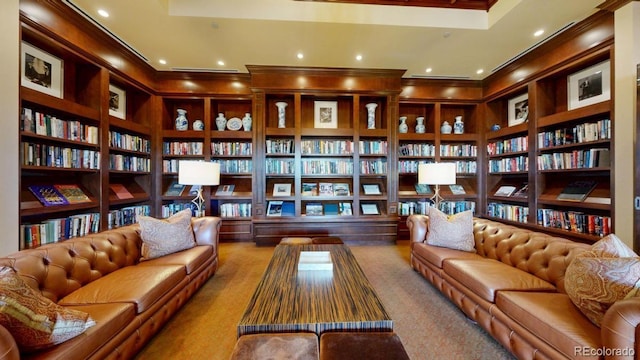 sitting room with built in features, carpet floors, ornamental molding, wall of books, and recessed lighting