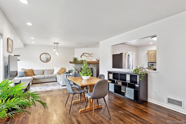 dining space with baseboards, visible vents, dark wood finished floors, recessed lighting, and a fireplace