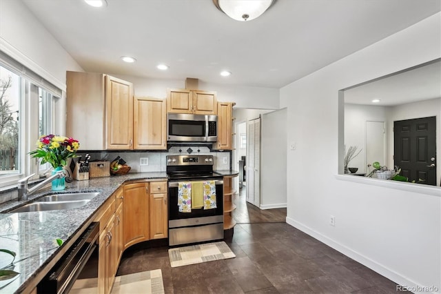 kitchen with light brown cabinetry, a sink, stainless steel appliances, decorative backsplash, and baseboards