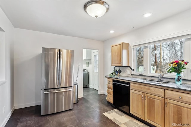 kitchen featuring dark stone counters, washer / clothes dryer, freestanding refrigerator, a sink, and dishwasher