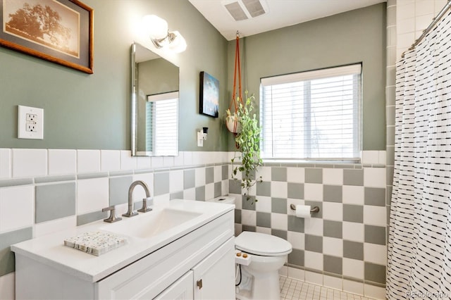 full bath featuring tile walls, toilet, visible vents, and a wealth of natural light