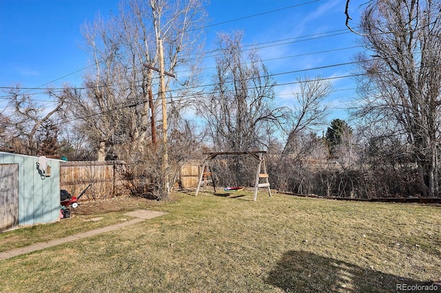 view of yard with a storage shed, an outdoor structure, a playground, and a fenced backyard