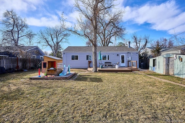 rear view of property with a deck, fence, an outdoor structure, and a shed