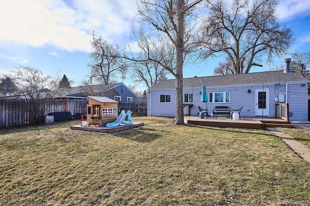 back of property with a deck, a playground, a yard, and a fenced backyard