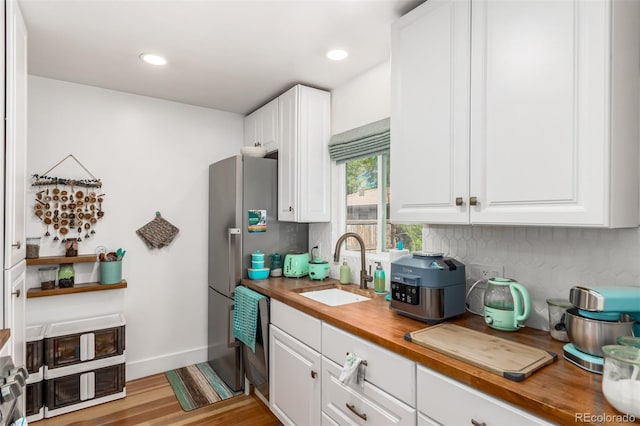 1160 S Monroe St, Denver, CO 80210 - kitchen with butcher block countertops, white cabinetry, light wood-style floors, decorative backsplash, and a sink