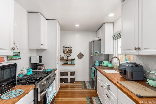 1160 S Monroe St, Denver, CO 80210 - kitchen featuring a sink, butcher block counters, white cabinetry, and stainless steel appliances