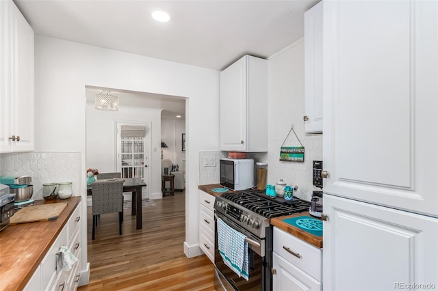 kitchen with stainless steel gas stove, white cabinetry, light wood-type flooring, and wood counters