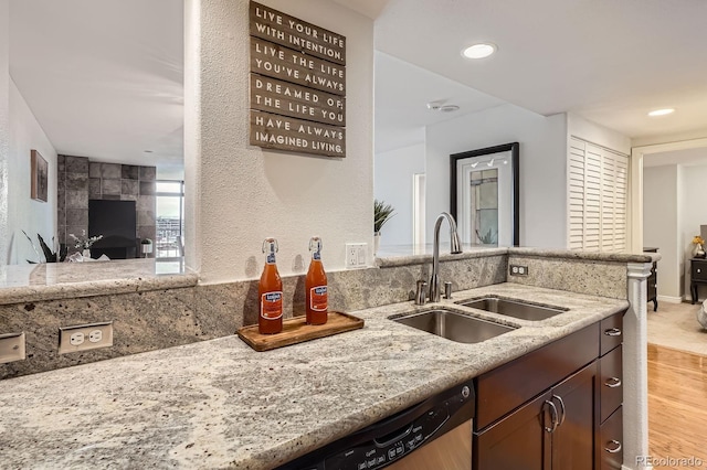 kitchen featuring a fireplace, a sink, light stone counters, a peninsula, and recessed lighting
