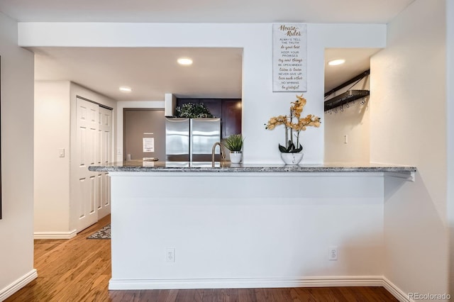 kitchen with freestanding refrigerator, recessed lighting, stone countertops, and wood finished floors
