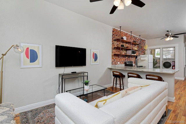 living area with a ceiling fan, baseboards, light wood finished floors, and washer and clothes dryer