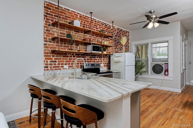 kitchen with white appliances, a sink, baseboards, and light wood-type flooring