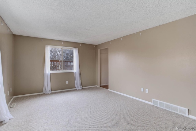 carpeted empty room featuring a textured ceiling