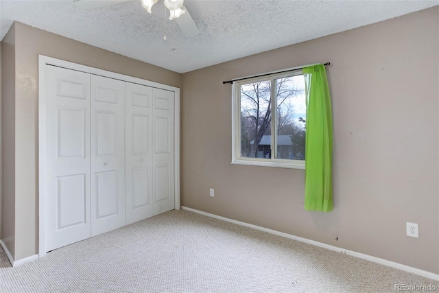 unfurnished bedroom with ceiling fan, a closet, light carpet, and a textured ceiling