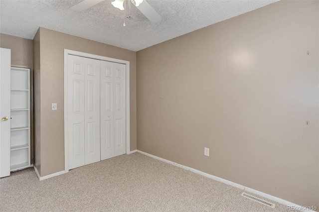 unfurnished bedroom with ceiling fan, a closet, light carpet, and a textured ceiling