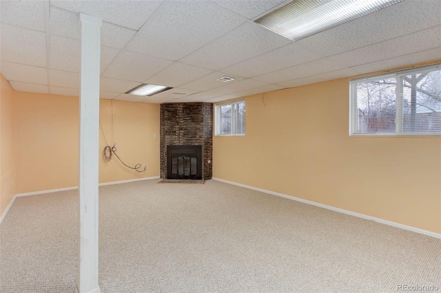 basement featuring a fireplace, a paneled ceiling, and carpet