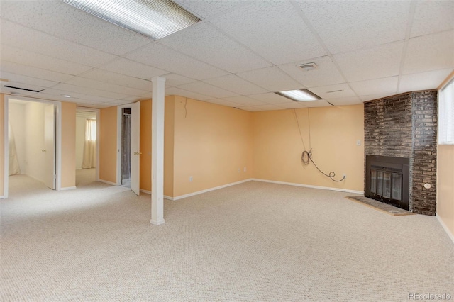 basement featuring a fireplace, a paneled ceiling, and carpet flooring