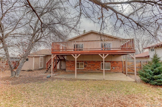 rear view of house featuring a wooden deck, a lawn, and a patio