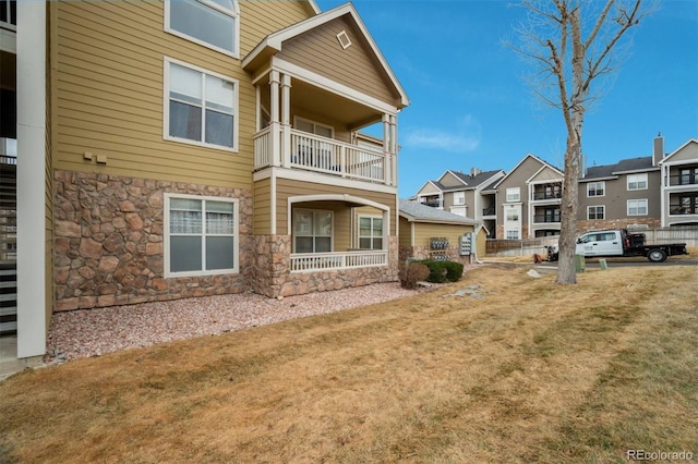 exterior space featuring a balcony, stone siding, and a residential view