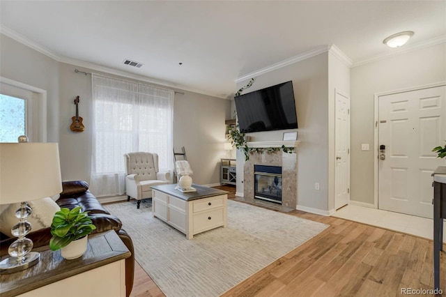 living area featuring plenty of natural light, a premium fireplace, light wood-type flooring, and visible vents