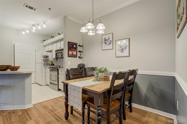 dining area with visible vents, baseboards, light wood-style floors, ornamental molding, and an inviting chandelier