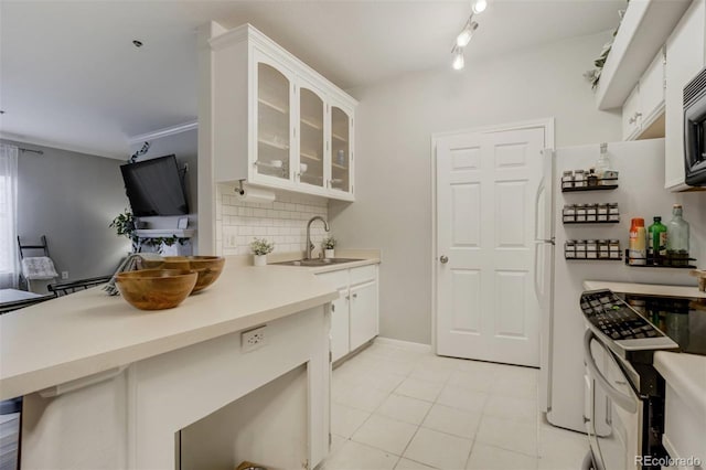 kitchen with decorative backsplash, glass insert cabinets, freestanding refrigerator, stainless steel electric range, and a sink