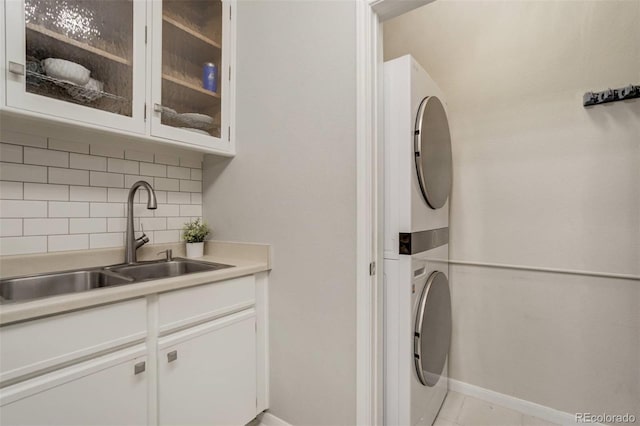 laundry area with stacked washer and dryer, a sink, laundry area, and baseboards