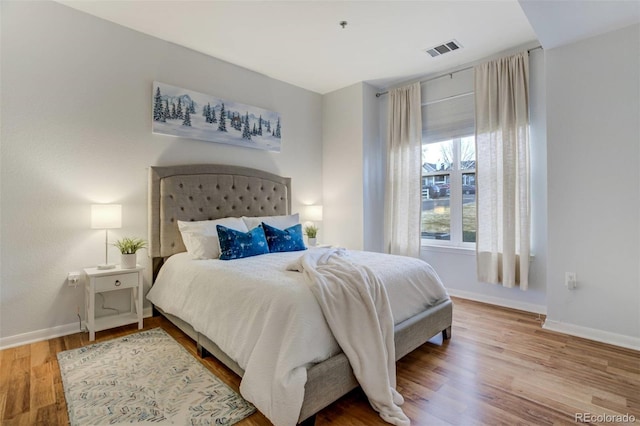 bedroom featuring visible vents, baseboards, and wood finished floors