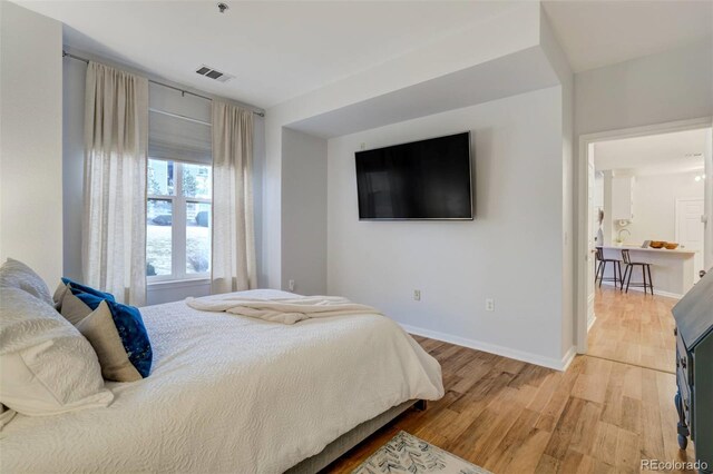 bedroom featuring light wood finished floors, visible vents, and baseboards